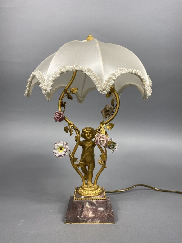 Pied de lampe en bronze doré soutenu par un angelot et ponctué de fleurettes en…