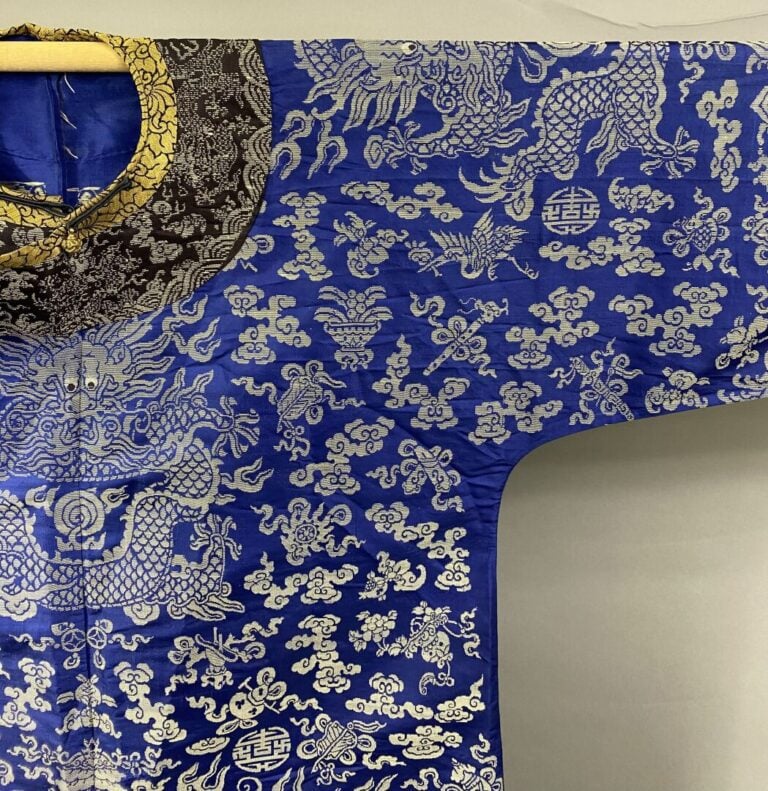 CHINE - XIXe siècle - Robe (jifu) en soie bleue brodée aux fils argentés de dra…