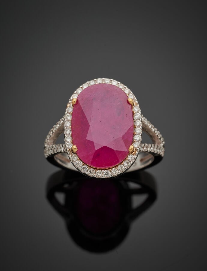 BAGUE en or gris (750‰) ajouré, serti d'un rubis ovale pesant 5,95 carats, ento…