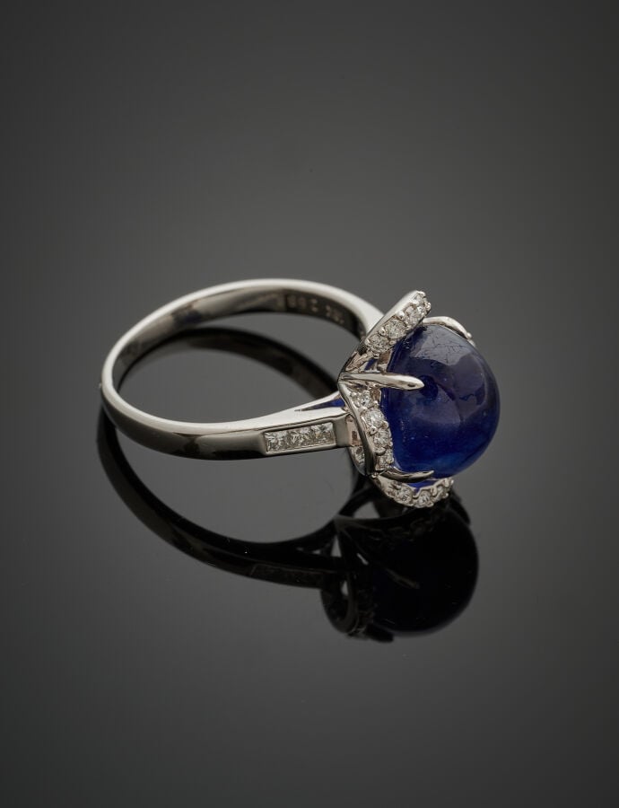 BAGUE en or gris (750‰) serti d'un saphir cabochon traité, entouré de diamants…