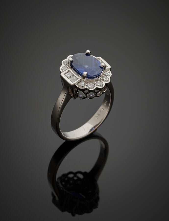 BAGUE « marguerite » en or gris (750‰) ajouré, serti d'un saphir ovale entouré…