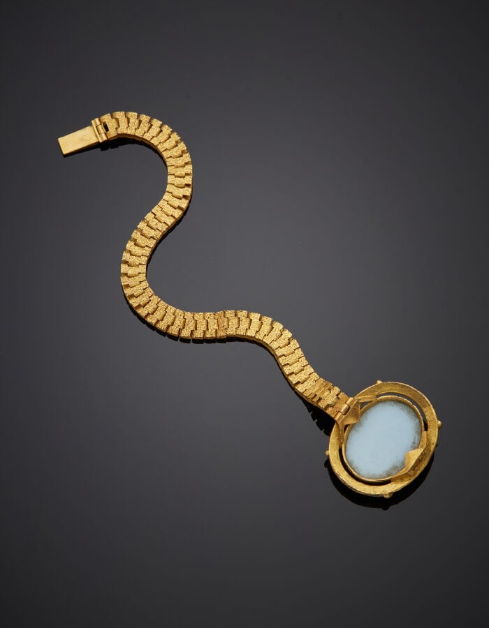 BRACELET en métal doré articulé et ciselé. Fermoir ovale serti d'une imitation…