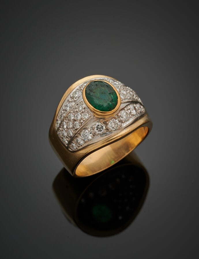 . Large BAGUE bombée en or jaune et or gris (750‰) serti d'une émeraude ovale e…