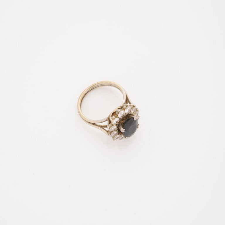 Bague marguerite en or gris (750) ornée d'un saphir de taille ovale facettée da…