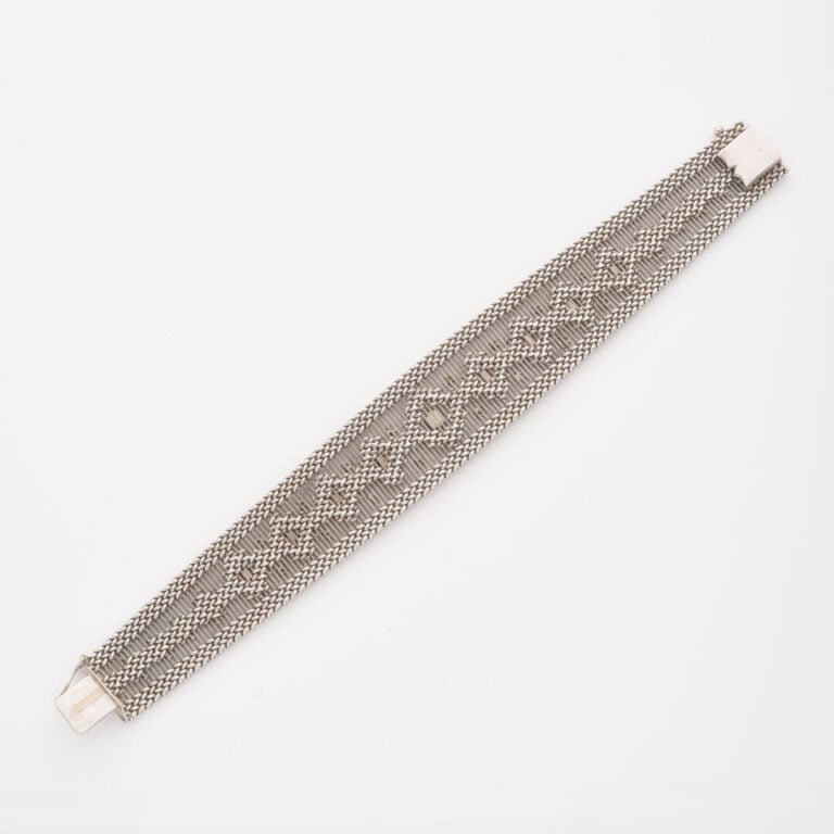 Bracelet ruban en or gris (750) à maille souple ajourée et tressée centrée d'un…