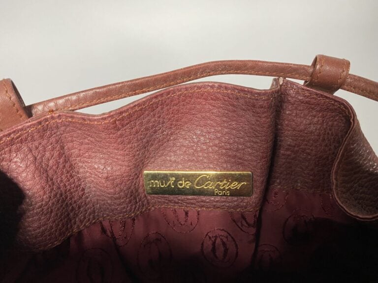 CARTIER - Sac bourse en cuir bordeaux « Must de Cartier », intérieur en tissu b…