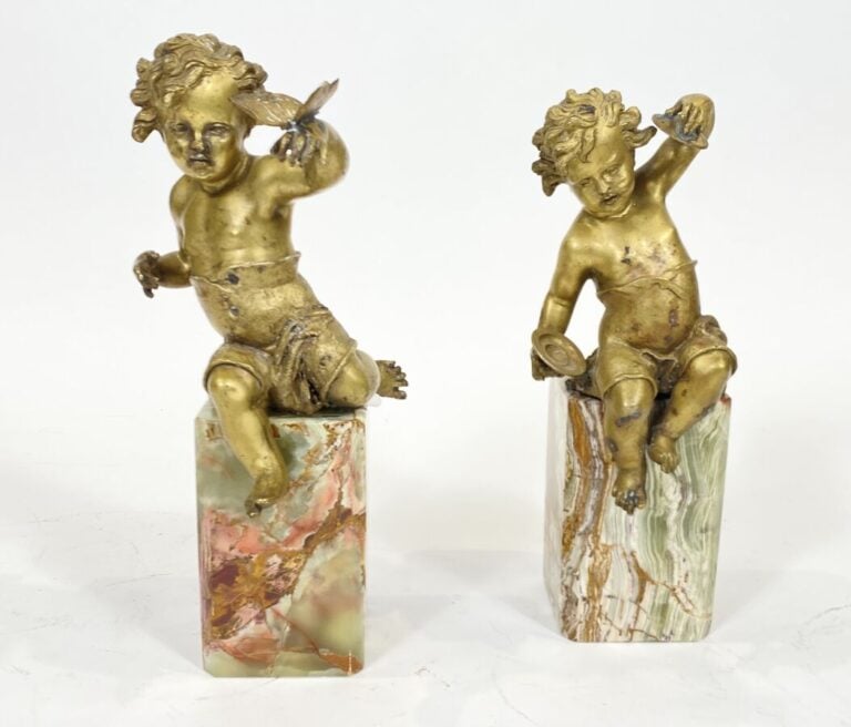 Deux amours en métal doré sur des socles en pierre à l'imitation de l'onyx - (a…