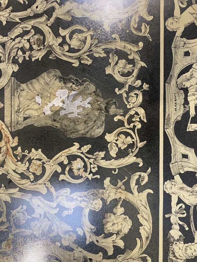 Grande table basse en métal à piétement feuillagé arqué ; le plateau en grisail…