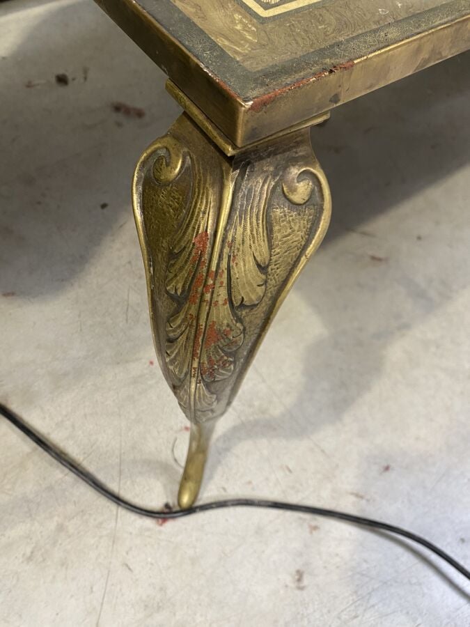 Grande table basse en métal à piétement feuillagé arqué ; le plateau en grisail…