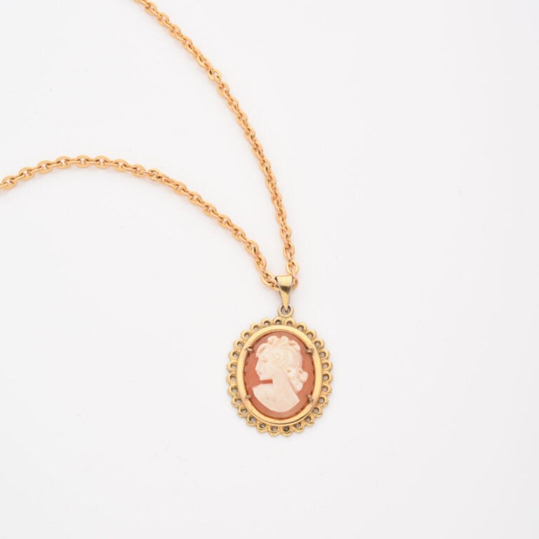 Sautoir à maille forçat en métal doré retenant un pendentif ovale en métal doré…