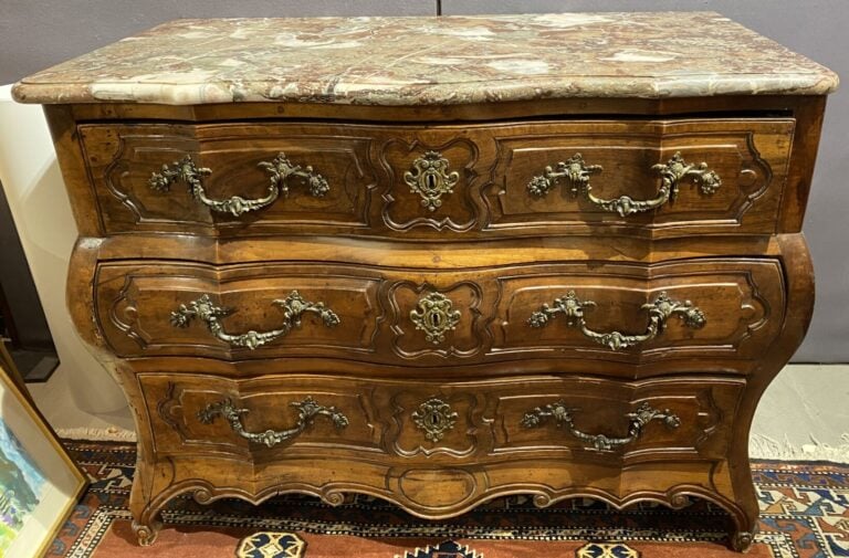 Commode en noyer mouluré et sculpté à façade légèrement arbalète ouvrant à troi…