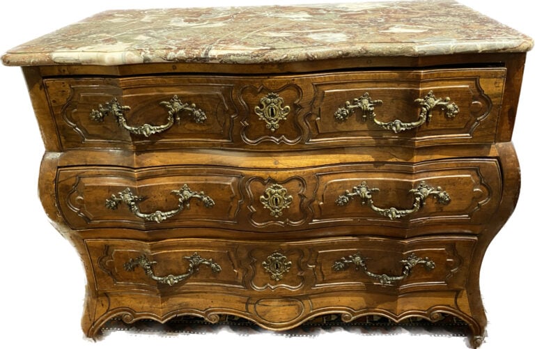 Commode en noyer mouluré et sculpté à façade légèrement arbalète ouvrant à troi…