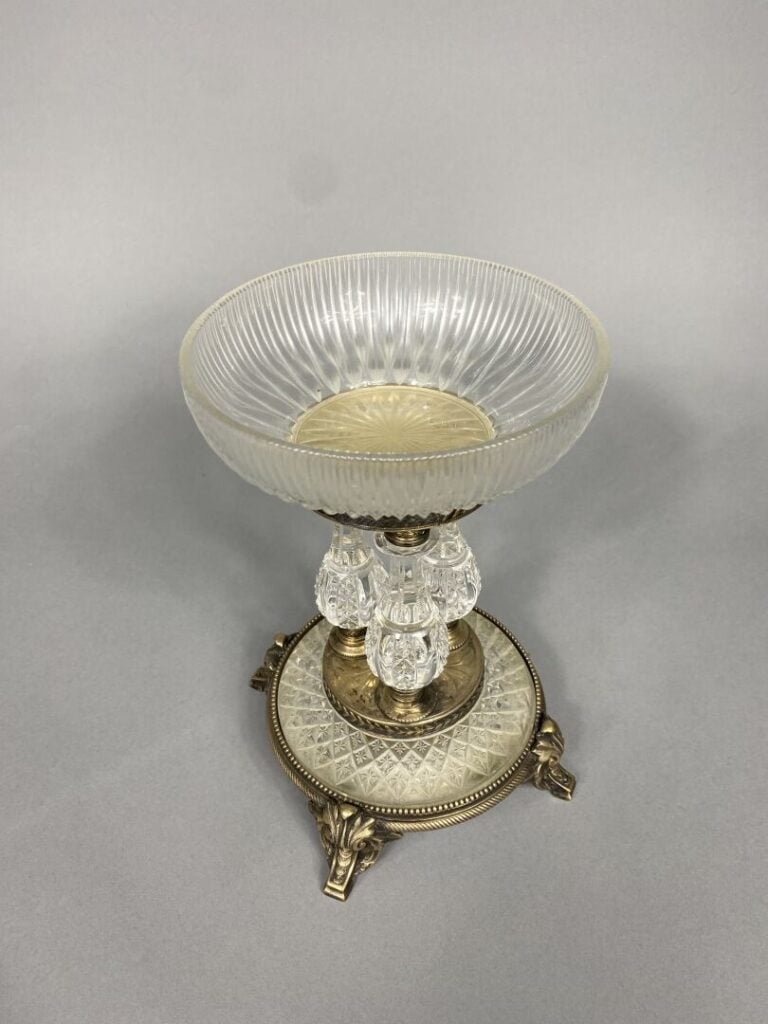 Coupe en verre taillé posant sur un piétement tripode en bronze à enroulements…