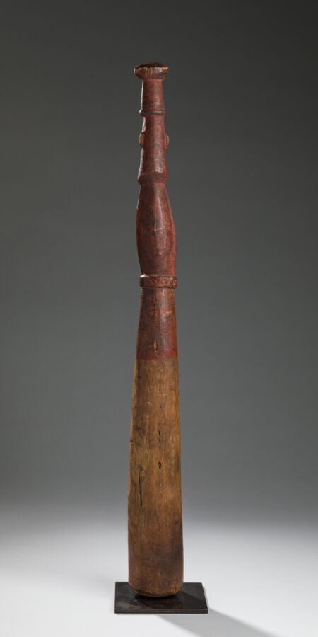 Ancien pilon sculpté d'un personnage dont les mains semblent tenir son sexe. La…