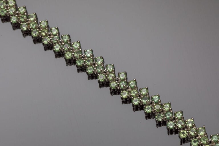 BRACELET en argent (925‰) serti de péridots ronds, formant chevrons. - Long.: 1…