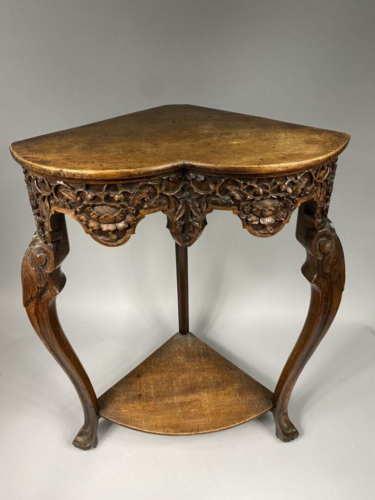 Encoignure en bois mouluré et sculpté de motifs feuillagés et fleurs, les pieds…