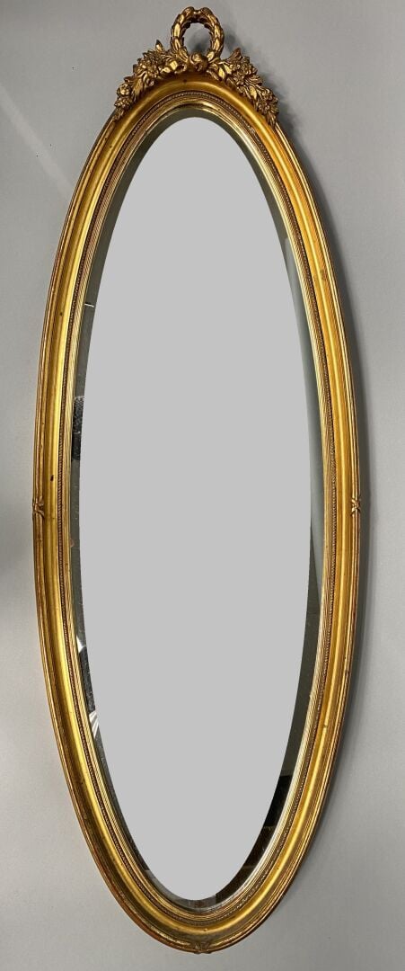 Miroir ovale en bois et composition doré à décor de frise surmonté d'une couron…