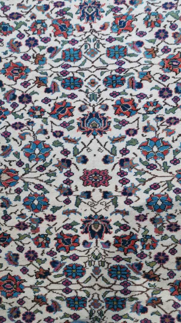 Perse - Tapis en laine à décor polychrome de rinceaux fleuris sur fond beige. L…