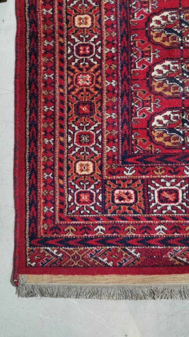 Tapis Boukhara royal à décor de colonnes de ghüls sur fond rouge. La bordure es…