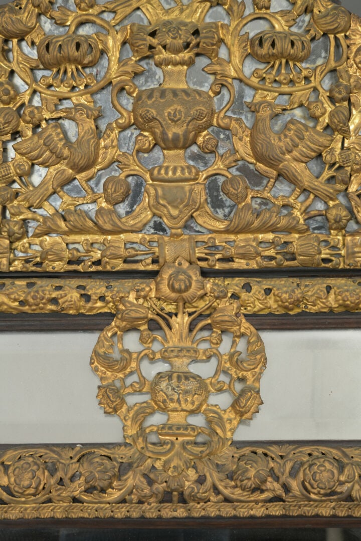 Grand miroir à parecloses en bois noirci mouluré et laiton repoussé à décor ric…