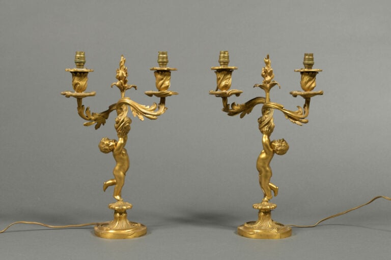 Paire de bougeoirs en bronze doré ciselé ornés d'un angelot soutenant deux bras…