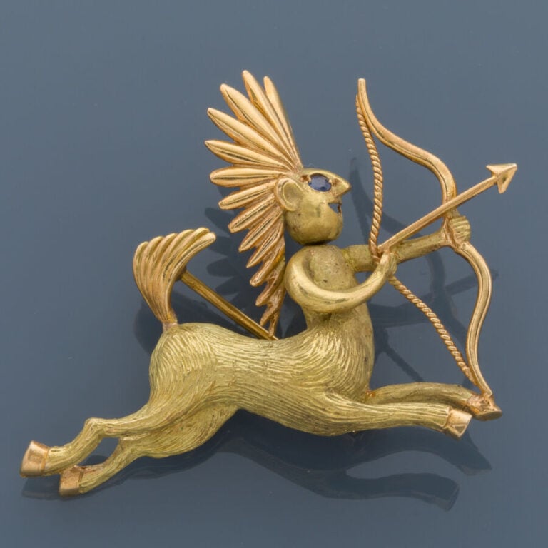 BROCHE « sagittaire » en or jaune (750‰) ajouré, ciselé et sculpté, l'oeil sert…