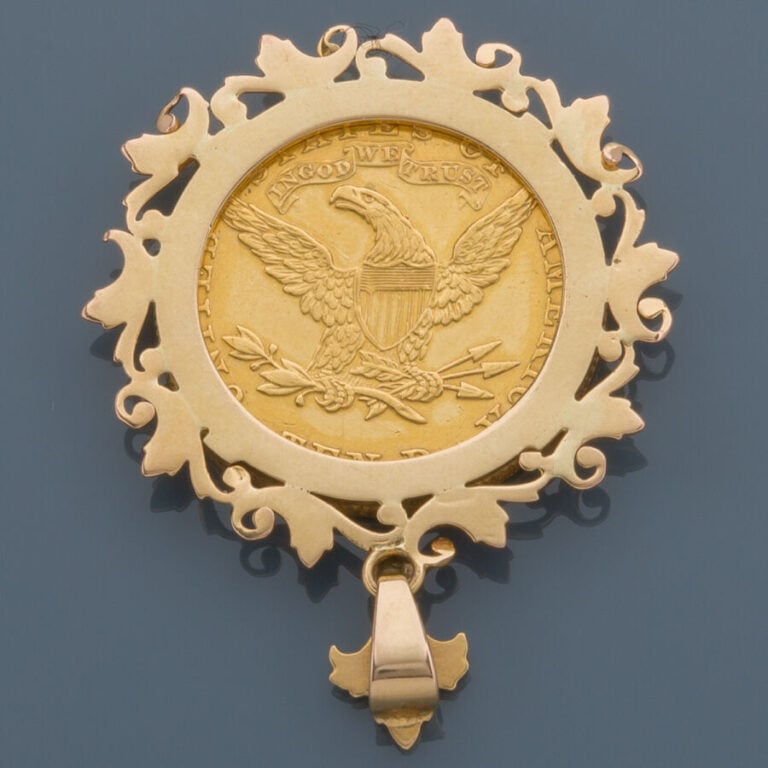PENDENTIF circulaire en or jaune (750‰) ajouré à décor de volutes retenant une…