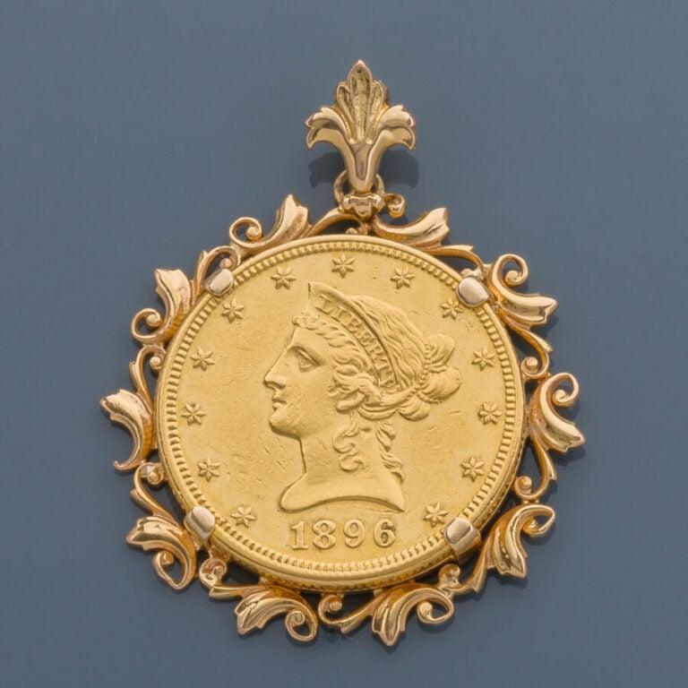PENDENTIF circulaire en or jaune (750‰) ajouré à décor de volutes retenant une…