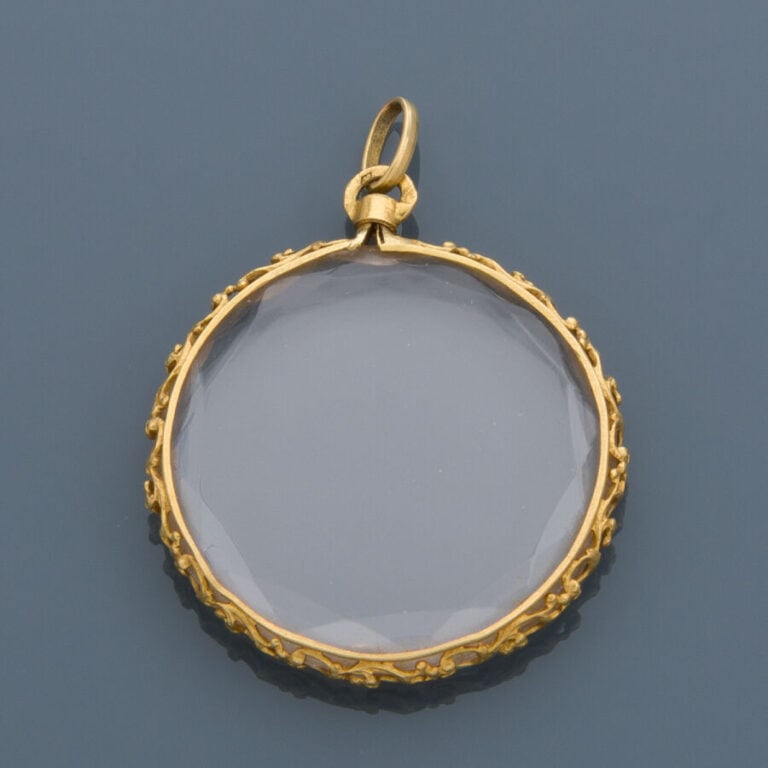 PENDENTIF porte-souvenir circulaire en or jaune (750‰) ajouré à décor de volute…