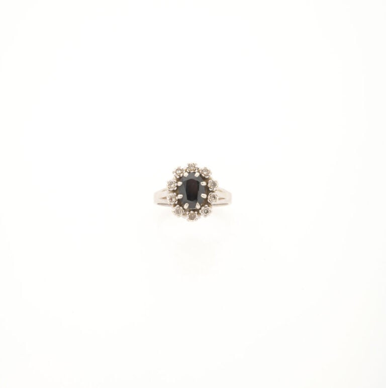 Bague en or gris (750) ornée d'un saphir foncé de taille ovale facettée en sert…