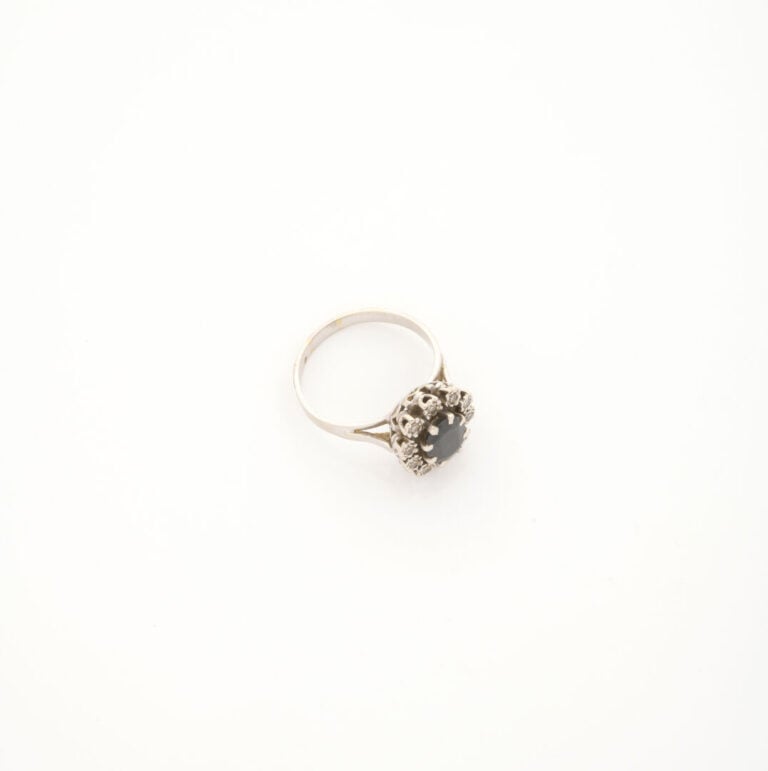 Bague en or gris (750) ornée d'un saphir foncé de taille ovale facettée en sert…