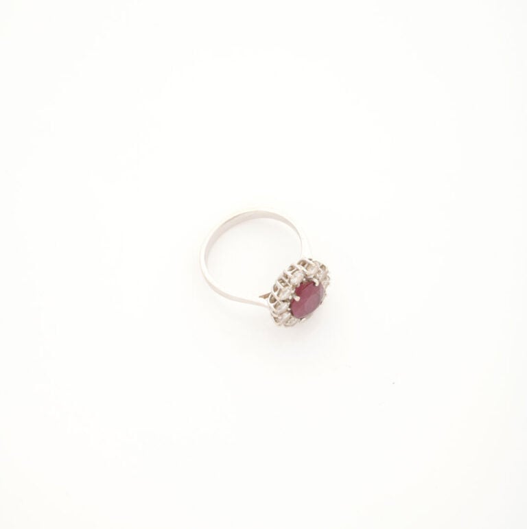 Bague marguerite en or gris (750) ornée d'un rubis de taille ovale facettée dan…