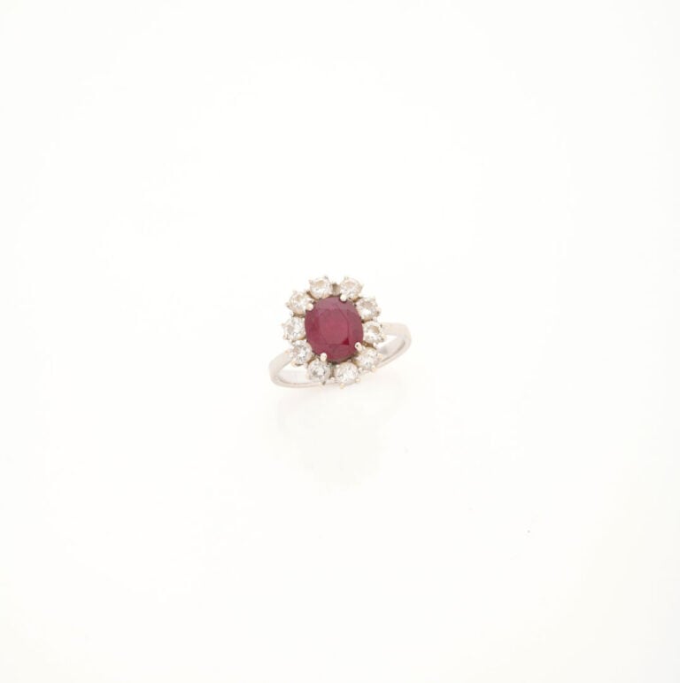 Bague marguerite en or gris (750) ornée d'un rubis de taille ovale facettée dan…
