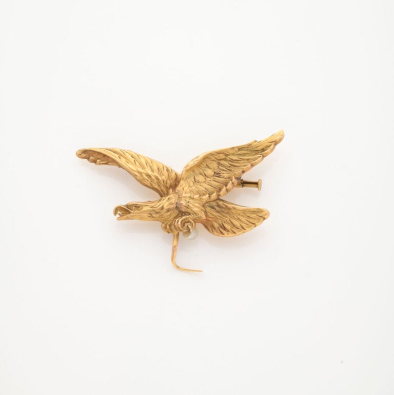 Broche en or jaune (750) figurant un aigle aux ailes déployées retenant une pet…