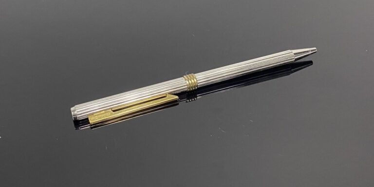 Christian DIOR - Stylo bille en métal argenté, le corps godronné, attributs en…