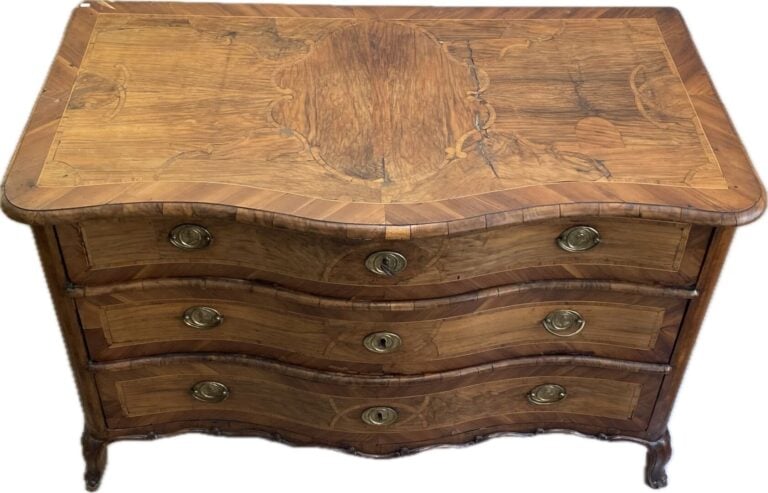 Commode en bois naturel à façade galbée ouvrant à trois tiroirs, ornementation…