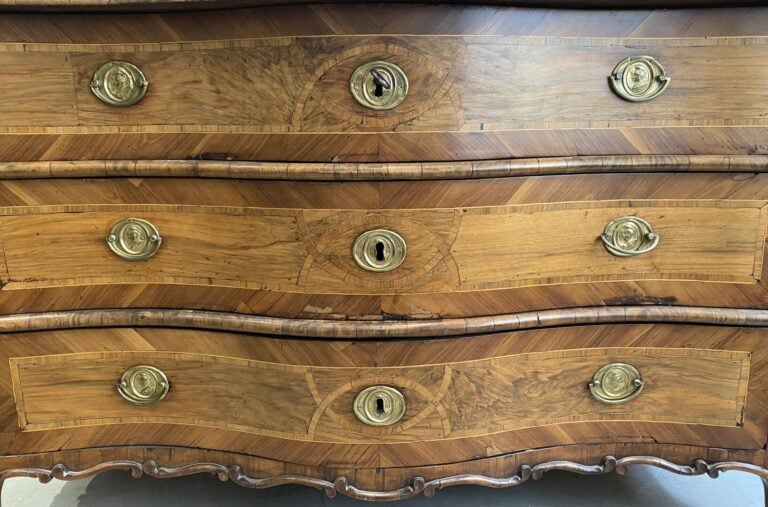 Commode en bois naturel à façade galbée ouvrant à trois tiroirs, ornementation…