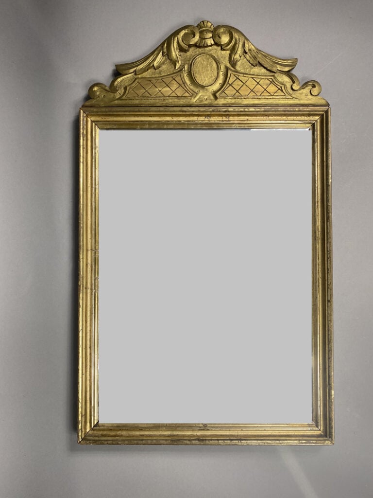 Miroir en bois mouluré et sculpté, le fronton à décor de volutes feuillagées -…