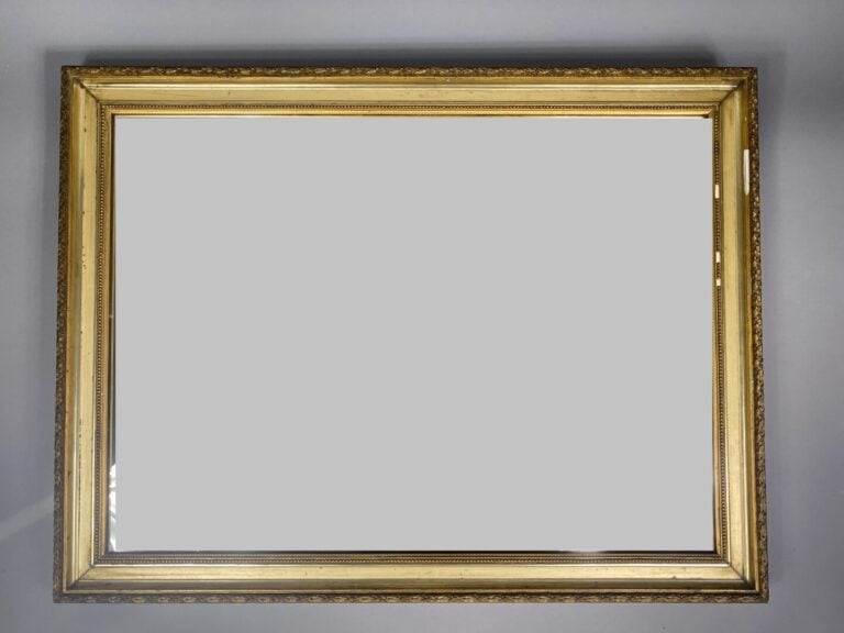 Miroir rectangulaire en bois et stuc doré à décor de frise de feuilles et entou…