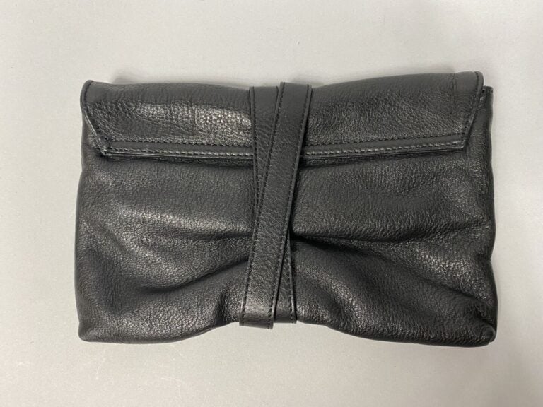 Pochette en cuir noir grainé, se ferme par un double lien et un fermoir pivotan…