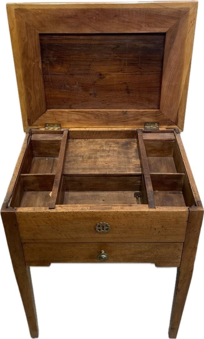 Table travailleuse en bois naturel reposant sur des pieds gainés, le plateau ma…