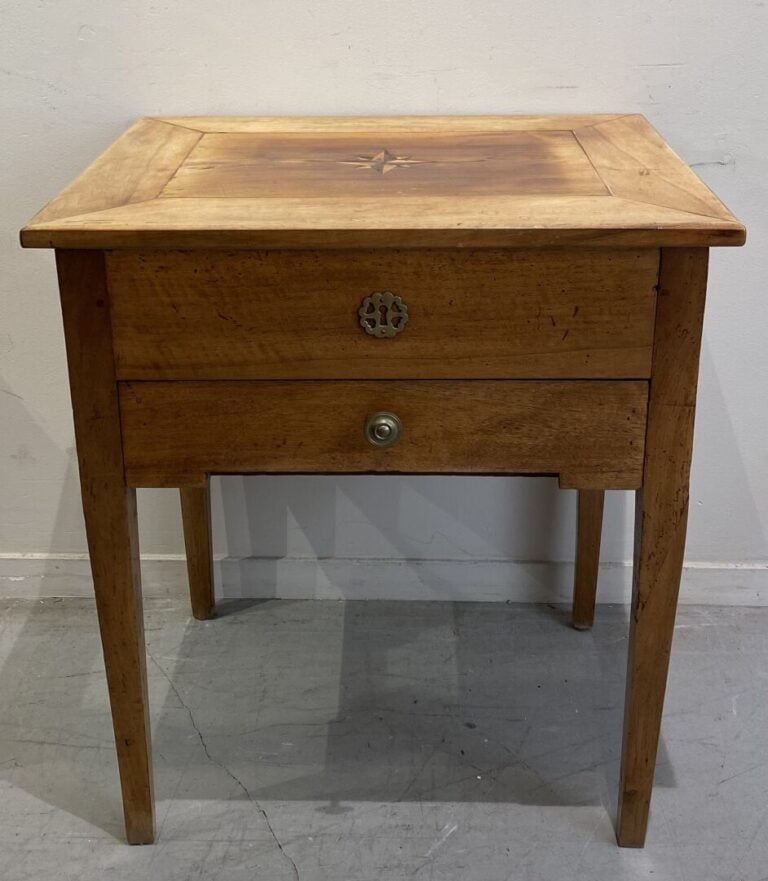 Table travailleuse en bois naturel reposant sur des pieds gainés, le plateau ma…