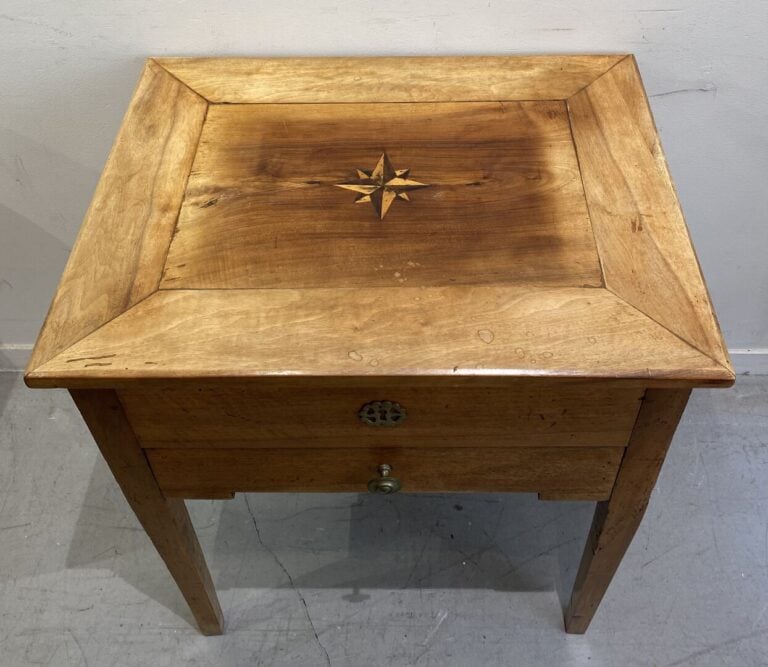 Table travailleuse en bois naturel reposant sur des pieds gainés, le plateau ma…
