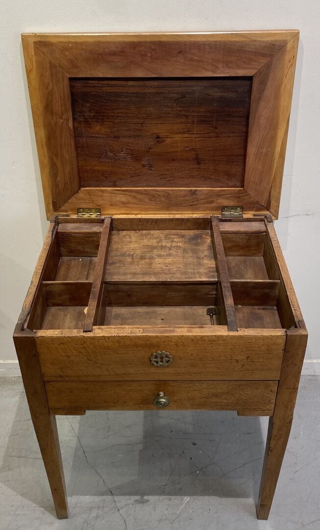 Table travailleuse en bois naturel reposant sur des pieds gainés, le plateau ma…