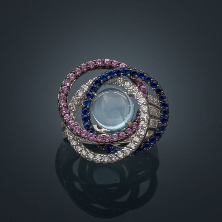 BAGUE "anneaux" en or gris et or noirci (750‰) ajouré, serti d'une topaze bleue…