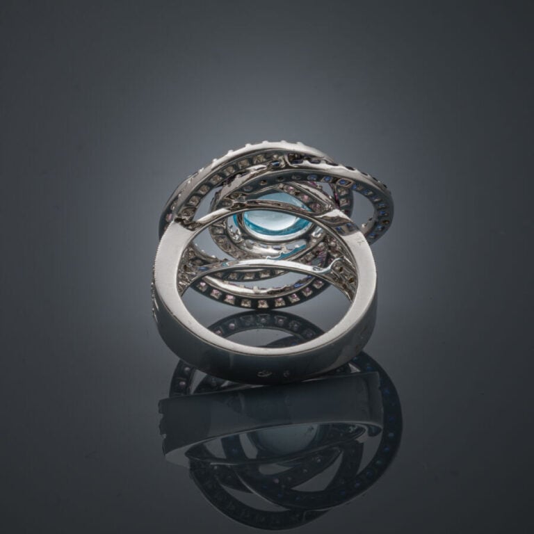 BAGUE "anneaux" en or gris et or noirci (750‰) ajouré, serti d'une topaze bleue…