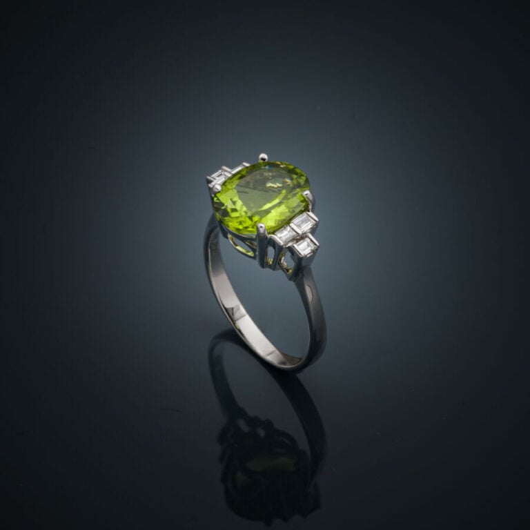 BAGUE en or gris (750‰) serti d'un péridot ovale épaulé de trois diamants taill…