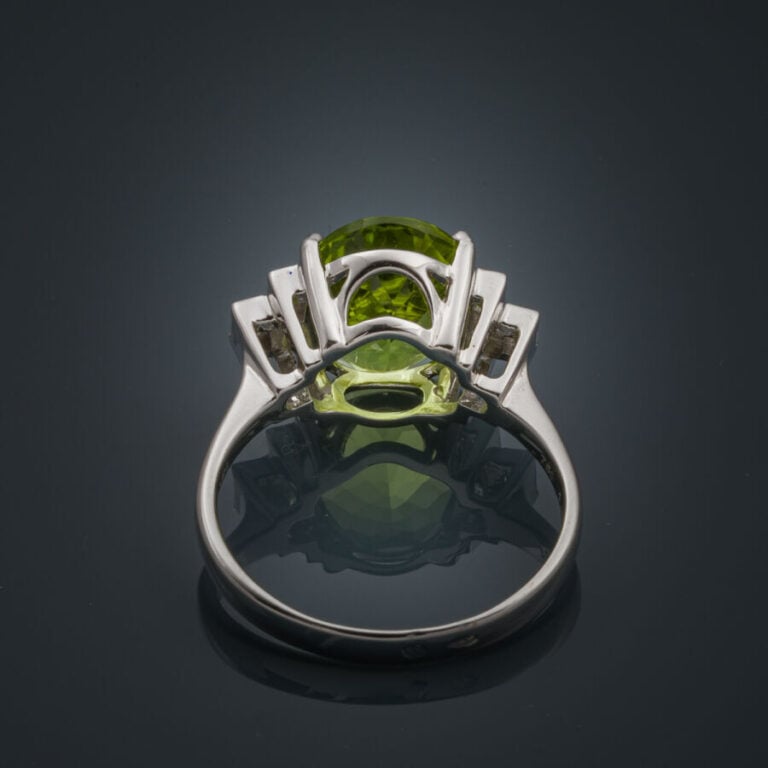 BAGUE en or gris (750‰) serti d'un péridot ovale épaulé de trois diamants taill…