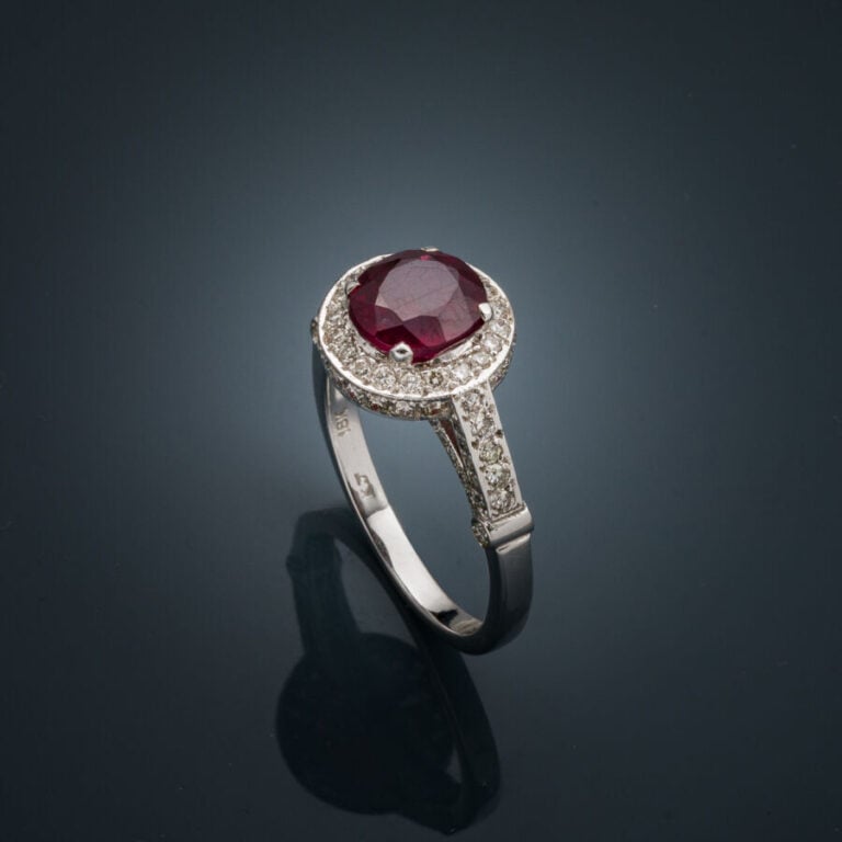 BAGUE en or gris (750‰) serti d'un rubis rond entouré et épaulé de diamants tai…