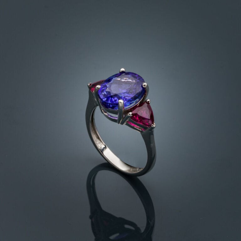 BAGUE en or gris (750‰) serti d'une tanzanite ovale, épaulé de rubellites (tour…